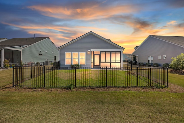 back of house at dusk featuring fence private yard and a yard
