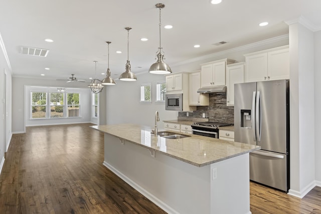 kitchen featuring decorative backsplash, crown molding, appliances with stainless steel finishes, under cabinet range hood, and a sink