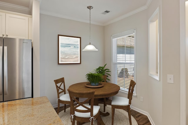 dining area with baseboards, visible vents, crown molding, and wood finished floors