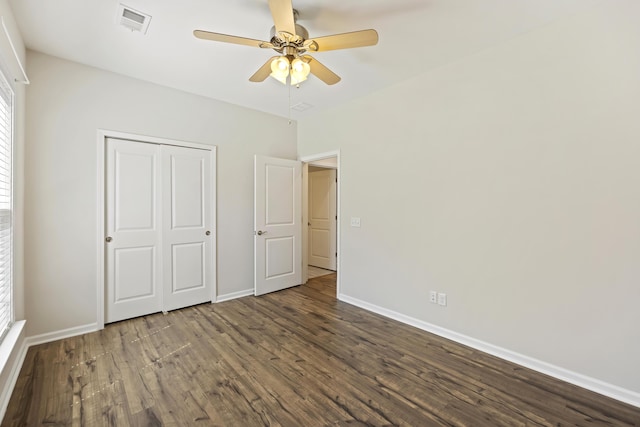 unfurnished bedroom featuring dark wood-type flooring, baseboards, visible vents, and a closet