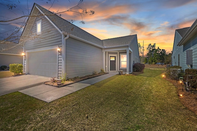 view of front facade with driveway, a shingled roof, and a lawn