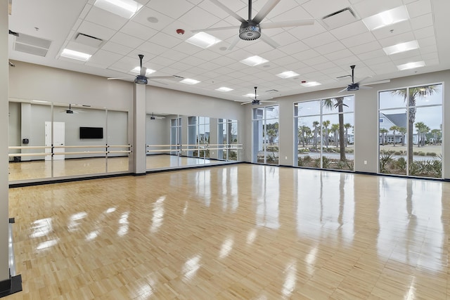 exercise room with a high ceiling, a ceiling fan, a drop ceiling, and visible vents