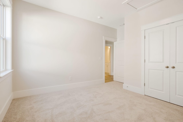 unfurnished bedroom featuring a closet and light colored carpet