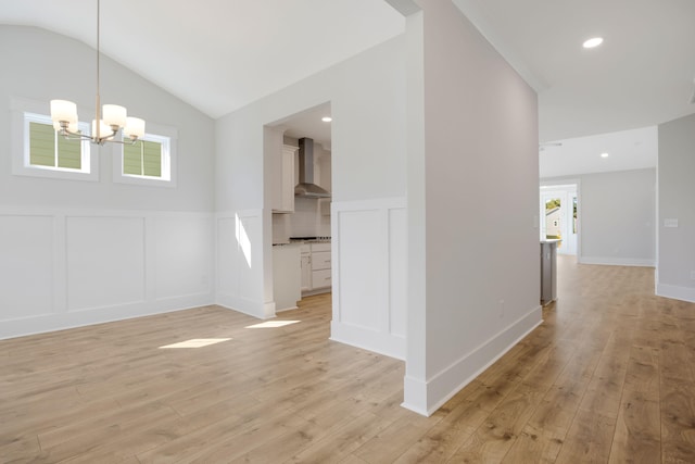 interior space with light hardwood / wood-style floors, a notable chandelier, and lofted ceiling