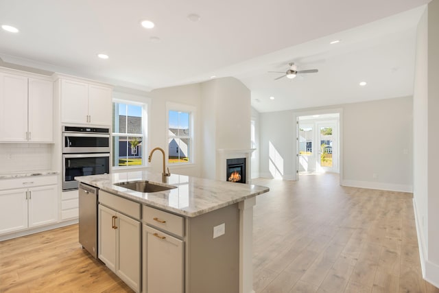 kitchen featuring light hardwood / wood-style floors, appliances with stainless steel finishes, sink, and a center island with sink