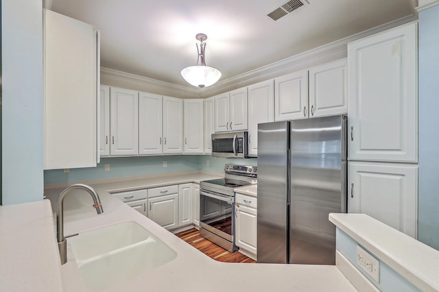 kitchen with stainless steel appliances, a sink, light countertops, and crown molding