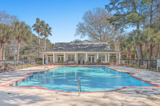 community pool featuring french doors, fence, and a patio