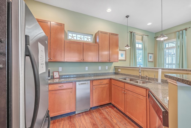 kitchen featuring appliances with stainless steel finishes, a sink, light wood-type flooring, hanging light fixtures, and recessed lighting