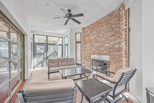 sunroom / solarium with a stone fireplace and ceiling fan