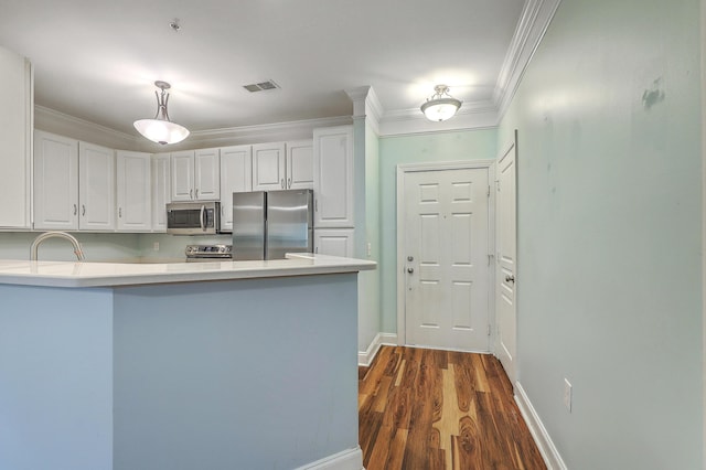 kitchen with appliances with stainless steel finishes, light countertops, white cabinetry, a peninsula, and dark wood-type flooring