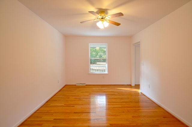 unfurnished room with light wood-style floors, visible vents, baseboards, and a ceiling fan