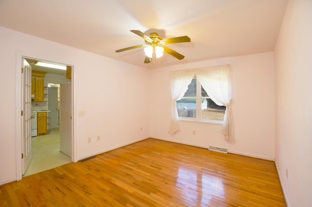 spare room with ceiling fan, light wood-style flooring, visible vents, and baseboards