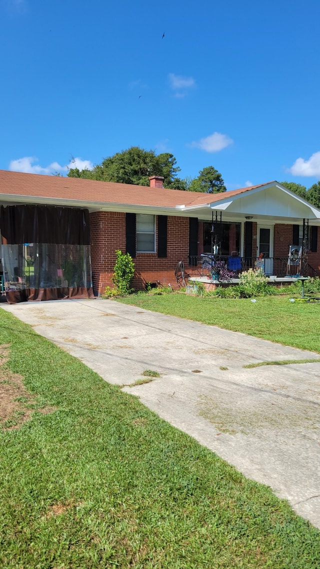 ranch-style home featuring a front lawn and a carport