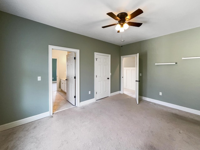 unfurnished bedroom featuring ensuite bath, light colored carpet, and ceiling fan