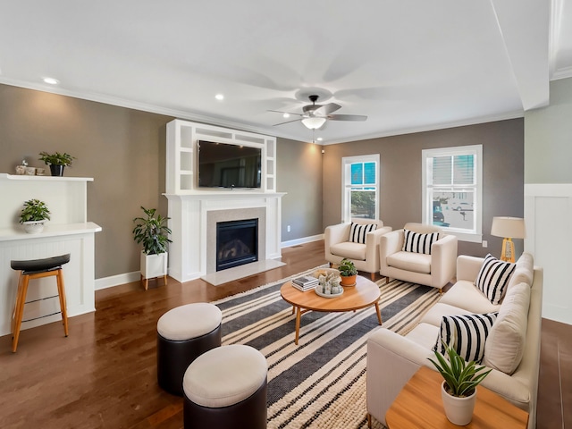 living room featuring dark wood-type flooring, ornamental molding, and ceiling fan