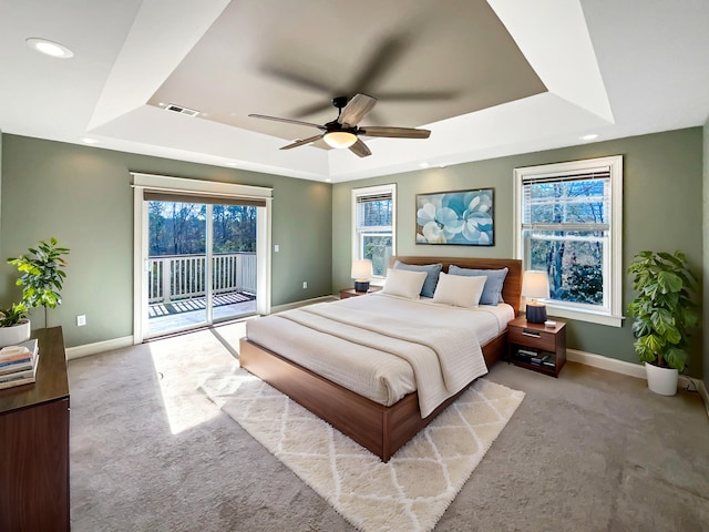 carpeted bedroom featuring access to outside, a raised ceiling, and ceiling fan