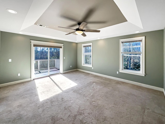 carpeted empty room featuring a raised ceiling and ceiling fan