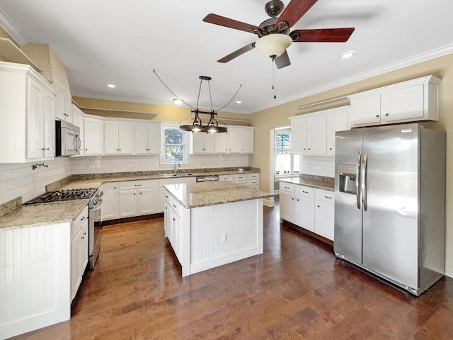 kitchen featuring sink, decorative light fixtures, a kitchen island, stainless steel appliances, and white cabinets