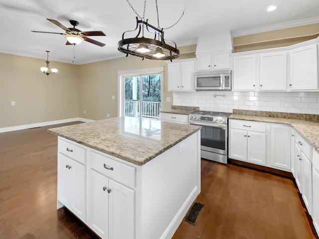 kitchen featuring stainless steel appliances, white cabinetry, hanging light fixtures, and a center island