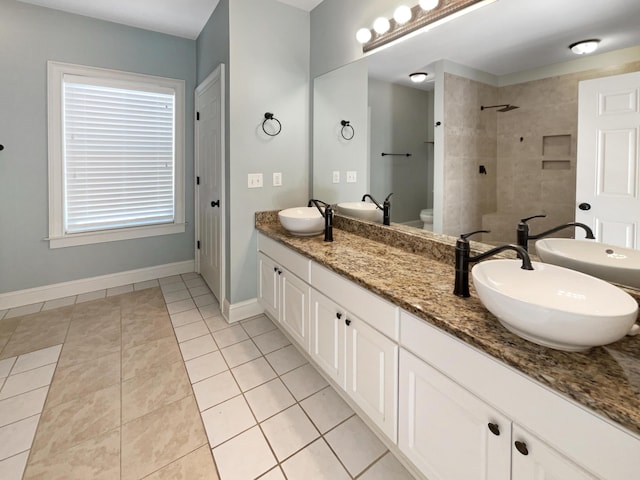 bathroom featuring vanity, toilet, tile patterned flooring, and a tile shower