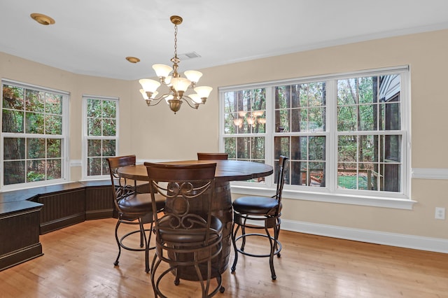 dining area featuring light wood-type flooring, an inviting chandelier, and plenty of natural light