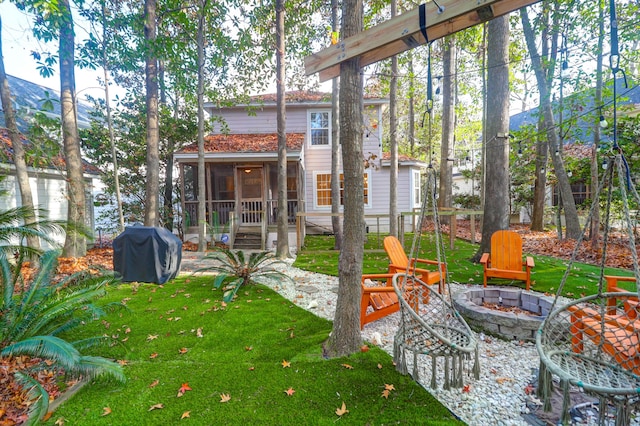 view of yard featuring a sunroom and an outdoor fire pit