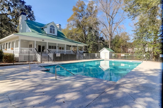 view of swimming pool featuring a patio and a storage shed