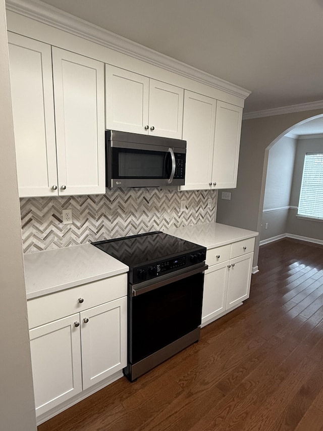 kitchen featuring dark wood-type flooring, white cabinetry, tasteful backsplash, crown molding, and electric range oven