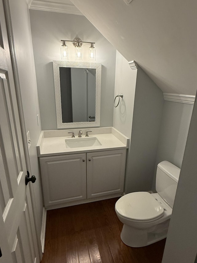 bathroom with vanity, vaulted ceiling, hardwood / wood-style floors, and toilet