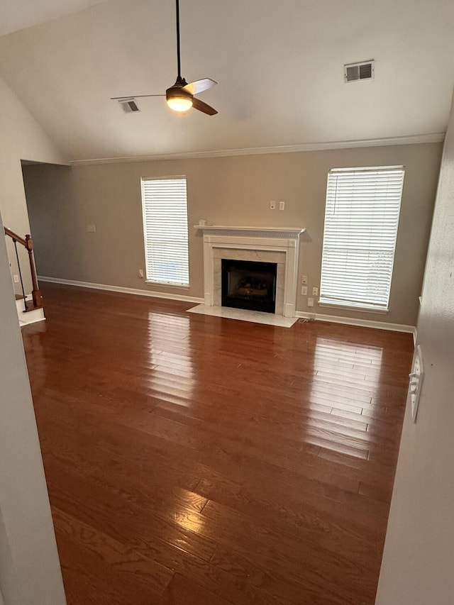 unfurnished living room featuring dark wood-type flooring, crown molding, vaulted ceiling, ceiling fan, and a premium fireplace