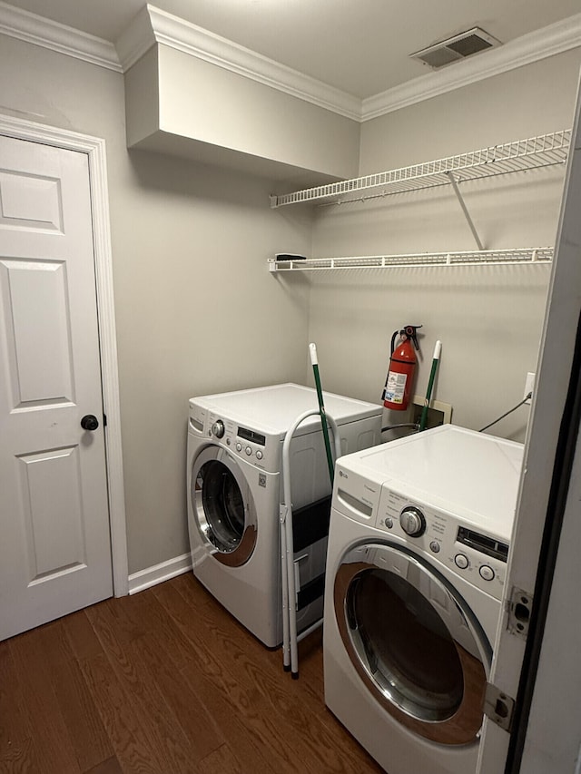 clothes washing area with ornamental molding, dark hardwood / wood-style flooring, and washer and dryer