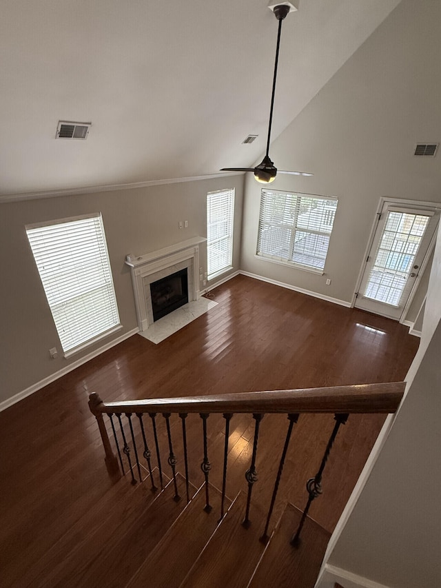 unfurnished living room featuring a high end fireplace, dark wood-type flooring, high vaulted ceiling, and ceiling fan