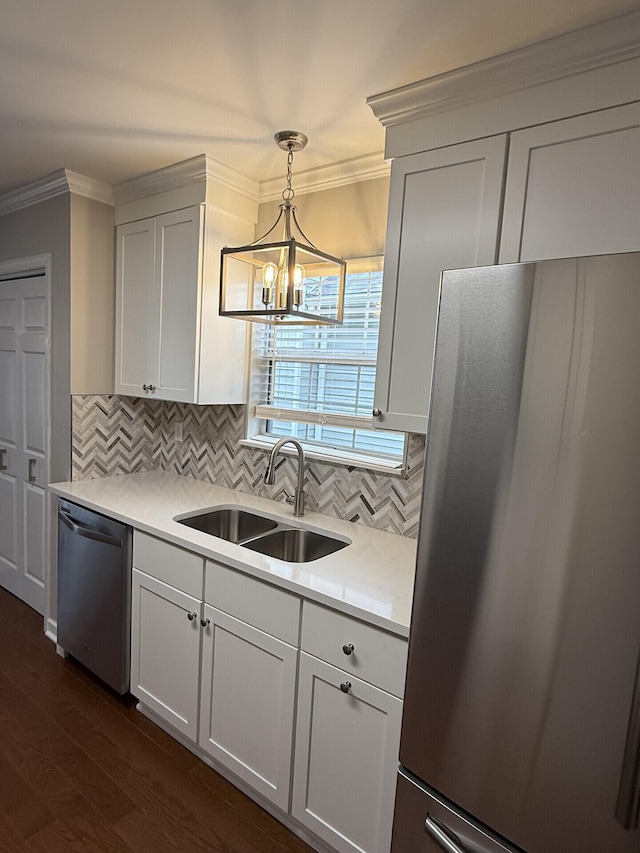 kitchen with pendant lighting, sink, white cabinets, ornamental molding, and stainless steel appliances