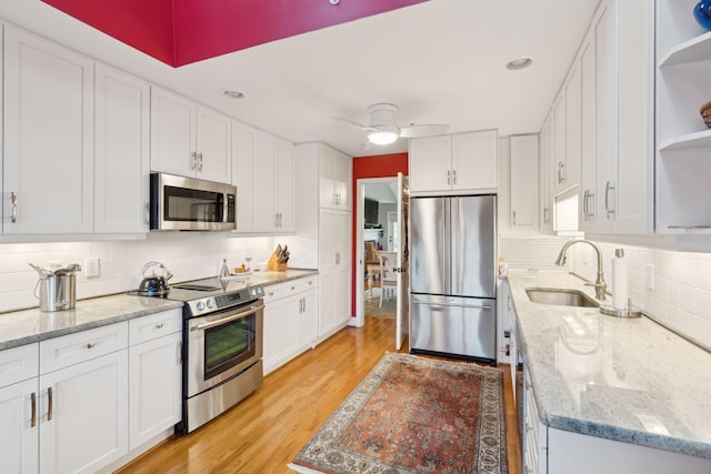 kitchen featuring white cabinets, decorative backsplash, light wood-type flooring, and stainless steel appliances