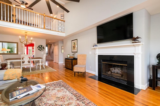 living room featuring beamed ceiling, hardwood / wood-style floors, a towering ceiling, and ceiling fan with notable chandelier