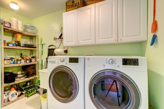 laundry area featuring cabinets, light tile patterned floors, and washing machine and dryer