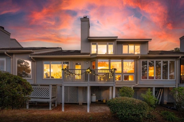 back house at dusk with a sunroom