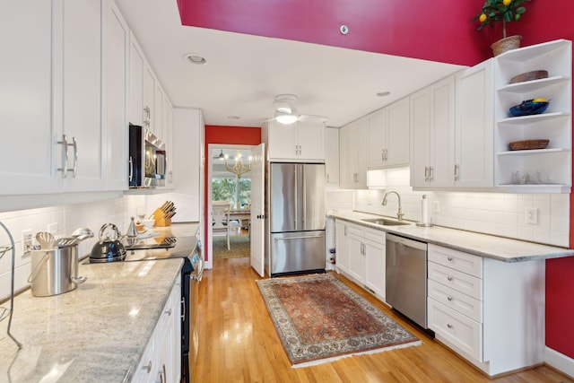 kitchen with white cabinetry, light stone countertops, sink, stainless steel appliances, and light hardwood / wood-style flooring