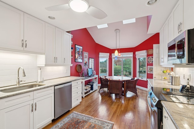 kitchen with sink, decorative light fixtures, lofted ceiling, white cabinets, and appliances with stainless steel finishes