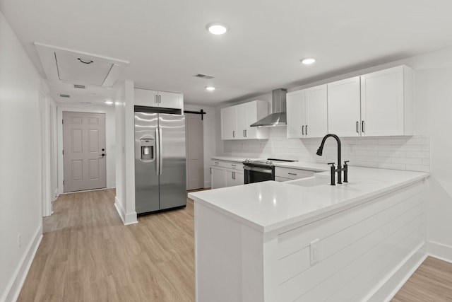 kitchen featuring wall chimney exhaust hood, stainless steel appliances, sink, light hardwood / wood-style flooring, and white cabinets