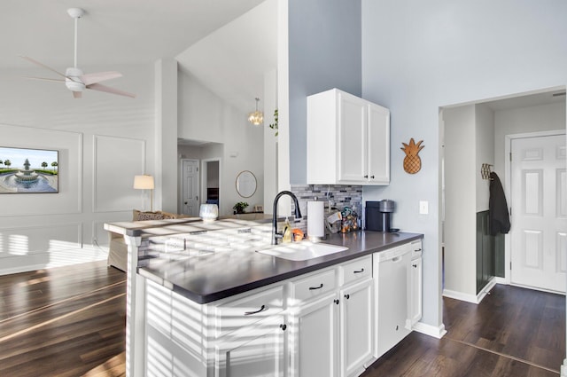 kitchen with tasteful backsplash, white cabinets, dishwasher, dark countertops, and a sink