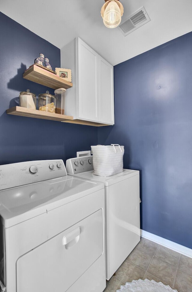 washroom with light tile patterned floors, visible vents, baseboards, independent washer and dryer, and cabinet space