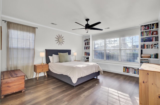 bedroom with dark wood-style floors, visible vents, and crown molding