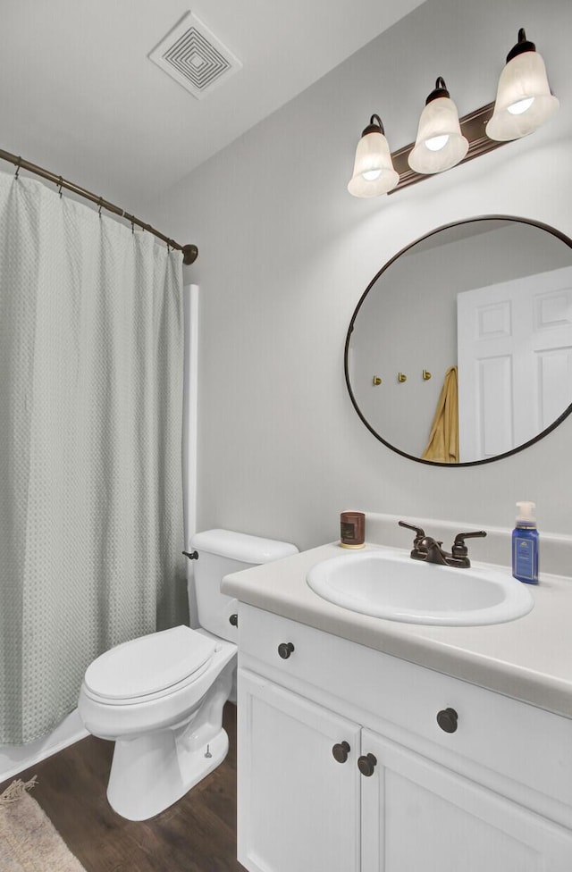 bathroom featuring curtained shower, visible vents, toilet, vanity, and wood finished floors