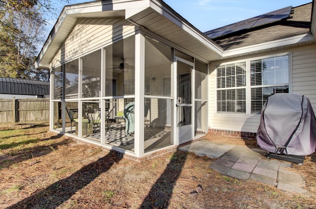 view of side of home featuring fence, a sunroom, and roof mounted solar panels