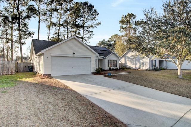 ranch-style home with an attached garage, solar panels, fence, driveway, and a front lawn