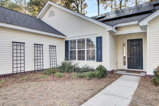 property entrance featuring roof with shingles and solar panels