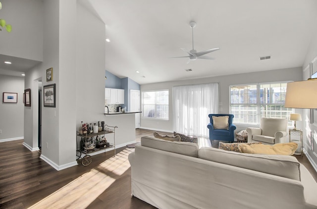 living area with dark wood finished floors, visible vents, ceiling fan, high vaulted ceiling, and baseboards