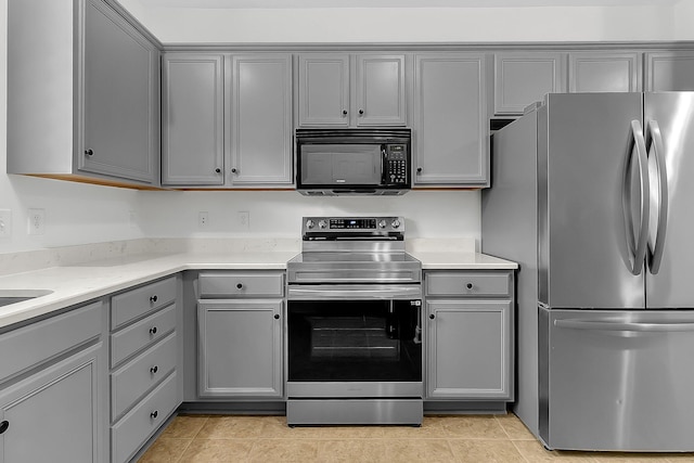 kitchen with appliances with stainless steel finishes, light tile patterned floors, and gray cabinetry