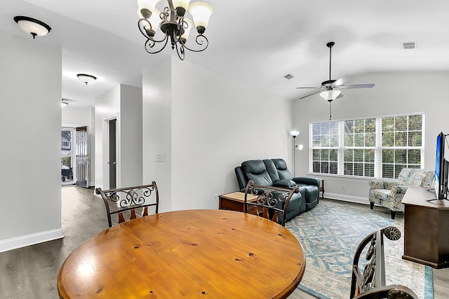 dining area with hardwood / wood-style flooring, ceiling fan with notable chandelier, and vaulted ceiling